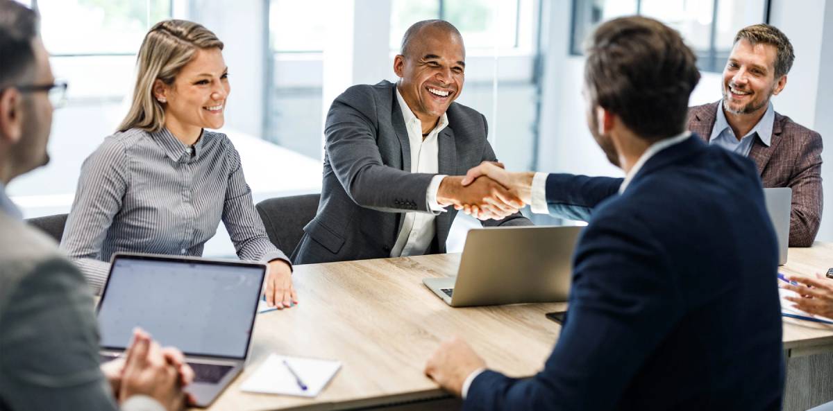 Business meeting with handshake and laptops.